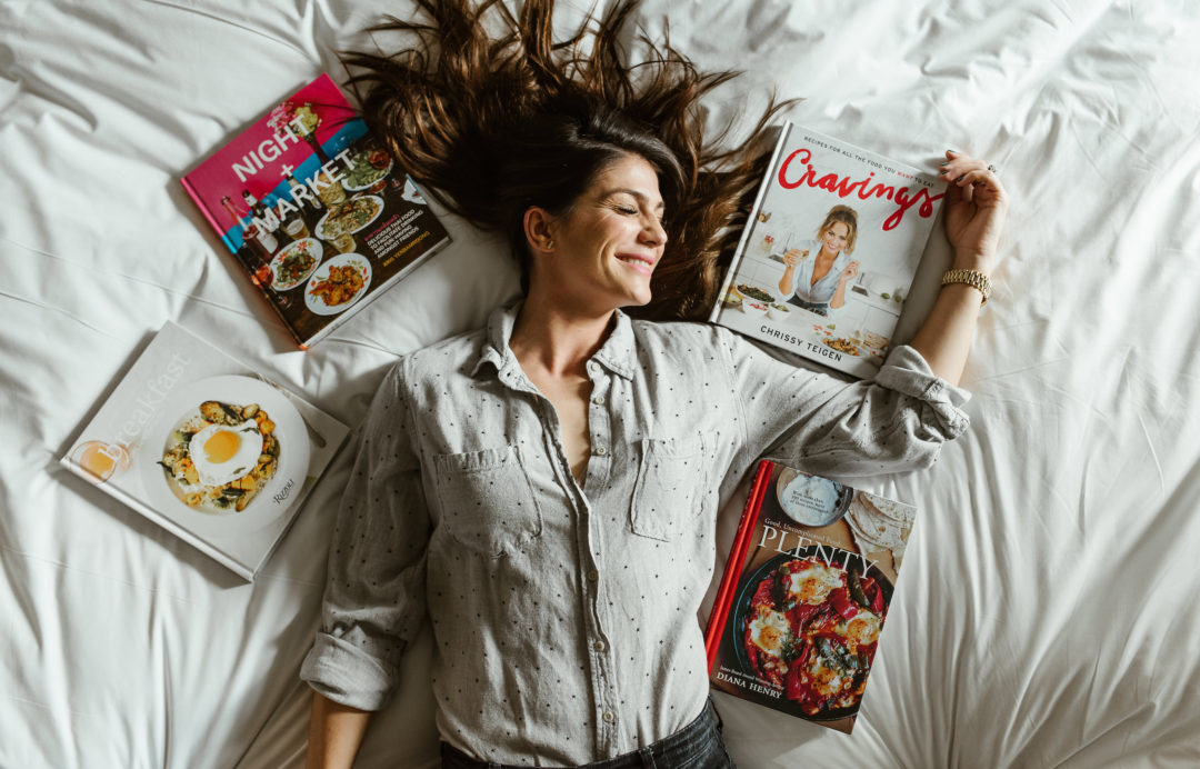 genevieve padalecki wife of jared padalecki of supernatural lies on bed with cookbooks around her