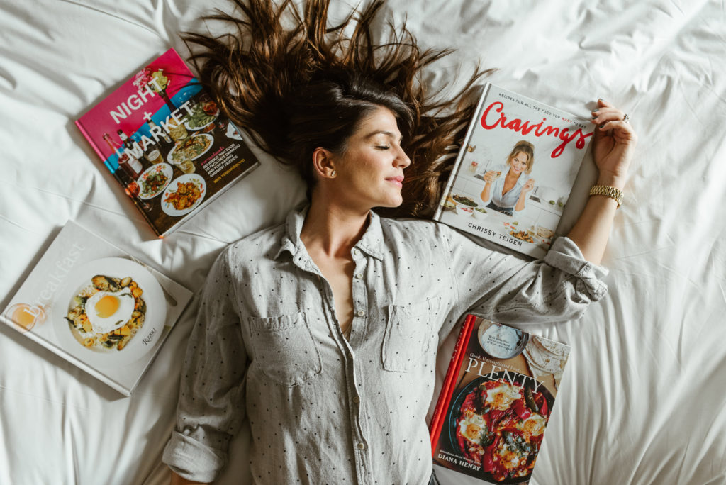 genevieve padalecki of now&gen wife of jared padalecki of supernatural lies on bed with cookbooks around her head