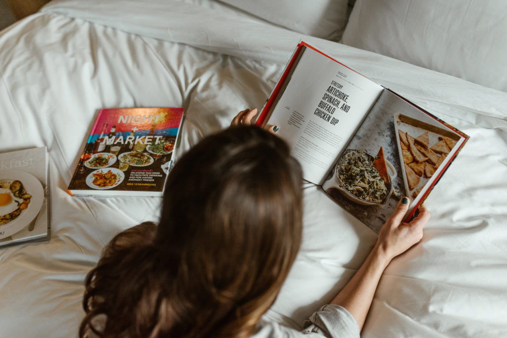 genevieve padalecki of now&gen wife of jared padalecki of supernatural lies on bed with cookbooks reading a cookbook